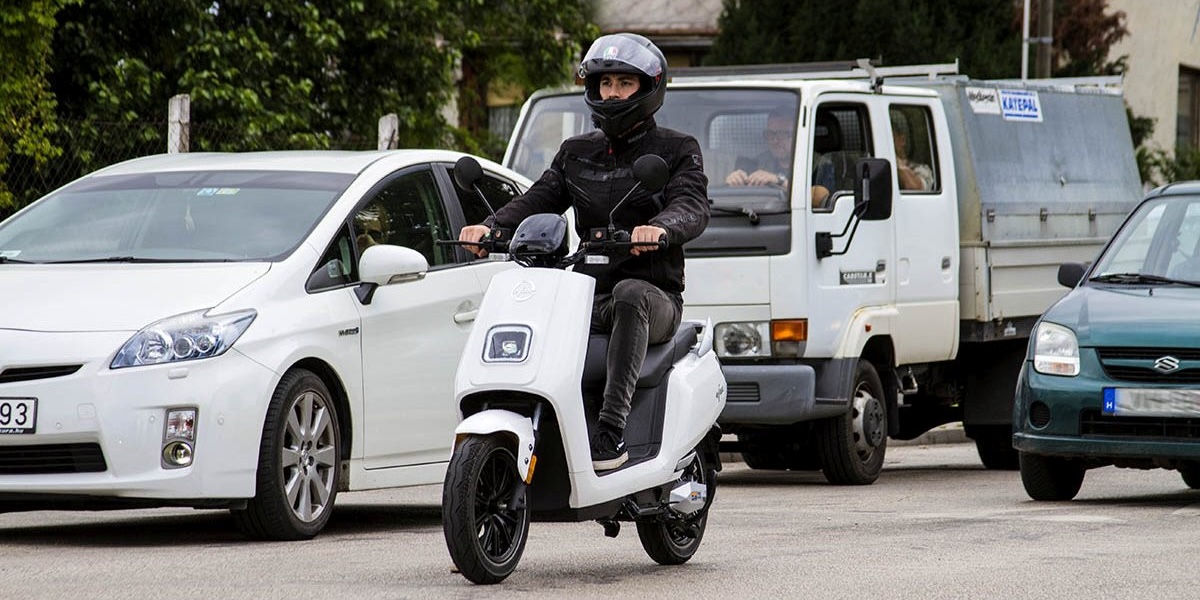 Robogós halad a forgalomban felnyitott sisakkal.