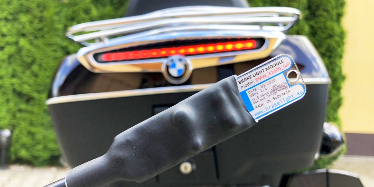 Egy féklámpa bekötésére szolgáló kábel, háttérben egy BMW-n található, világító, hátsó dobozon található kiegészítő féklámpával.